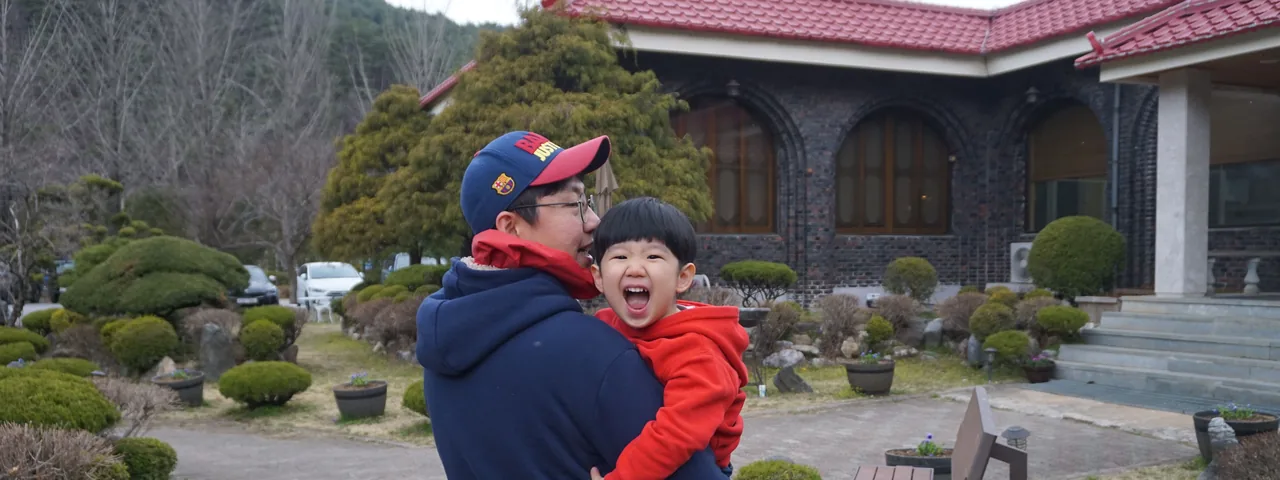 한국인 아버지가 아들을 안고 활짝 웃는 가족의 모습